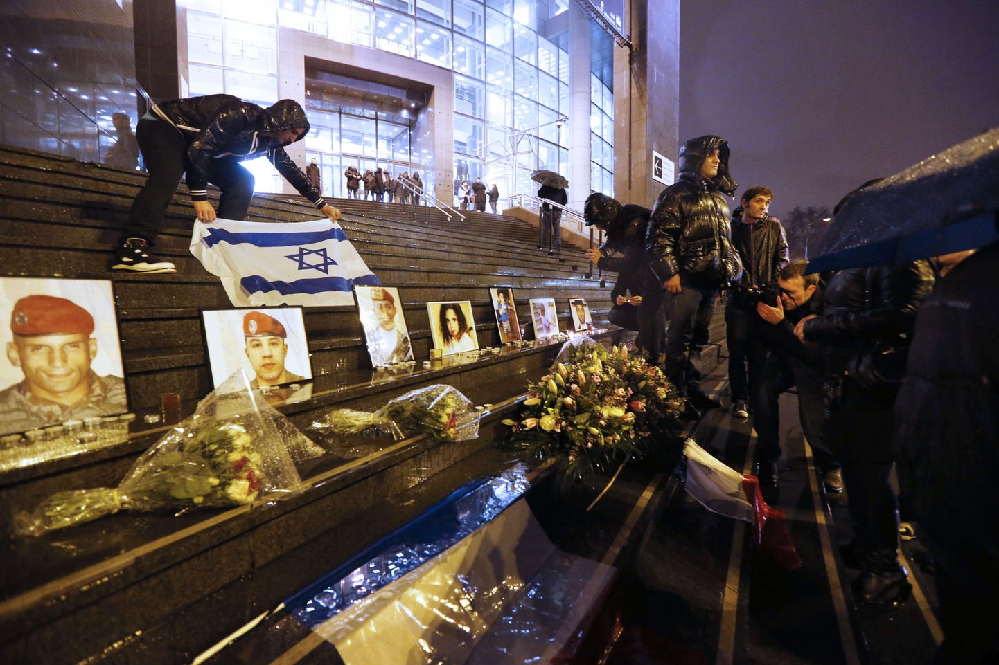 Mees asetab Iisraeli lipu Toulouse'i veresauna ohvrite piltide juurde Pariisis Opera-Bastille juures aasta pärast massitulistamist ehk 19. märtsil 2013.