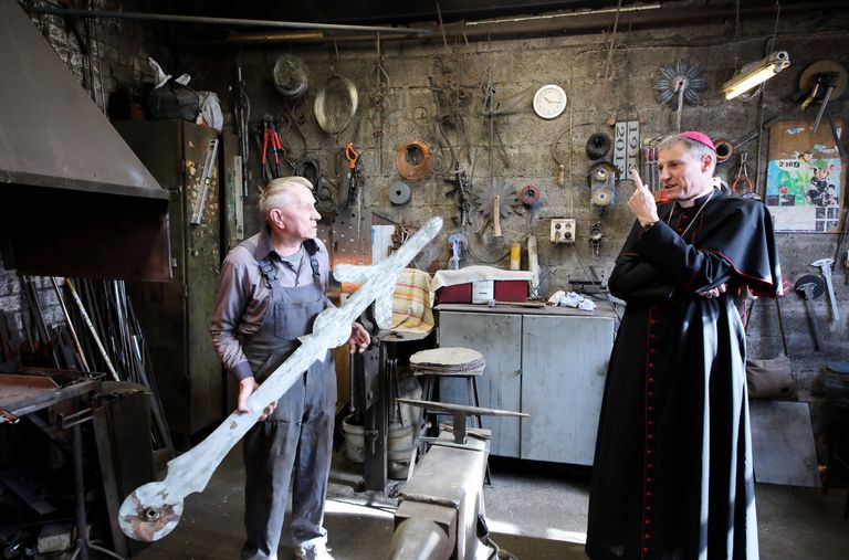 Глава Латвийской римско-католической церкви Збигнев Станкевич в мастерской, где реставрируют петушка. Работы по металлу выполняет кузнец Петерс Корольс.