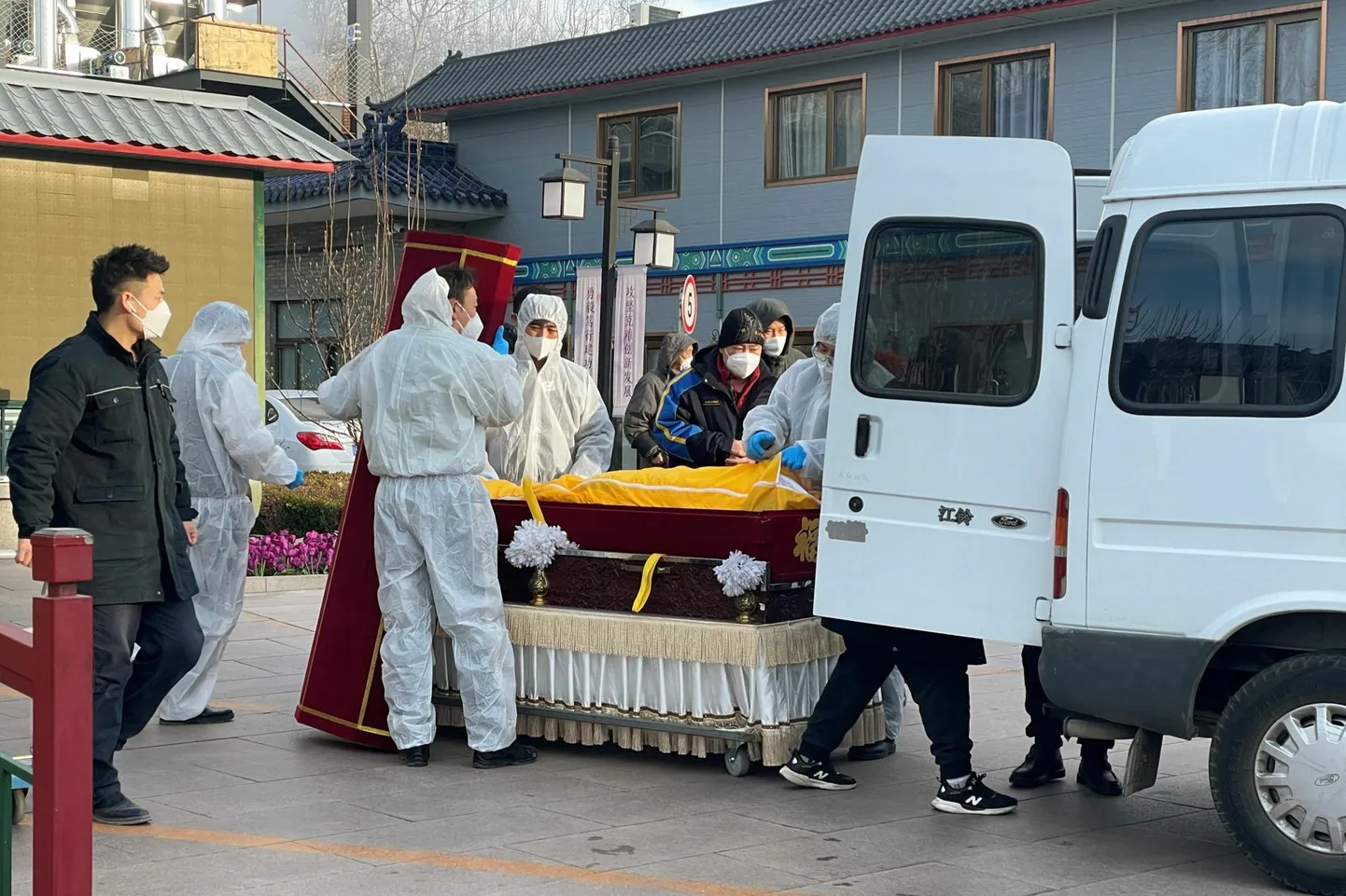 Kaitseülikondades töötajad transpordivad kirstus surnukeha matusebüroo juures Pekingis.