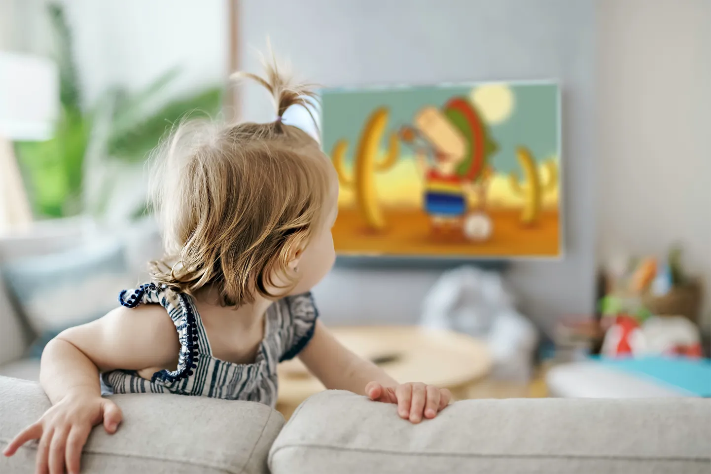 Ребенок смотрит по телевизору рекламу лимонада.