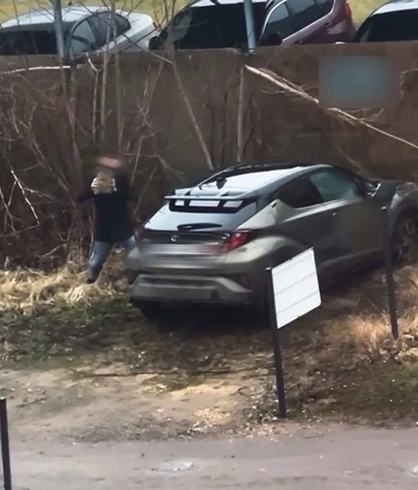 Мужчина выбивает камнем окно в автомобиле