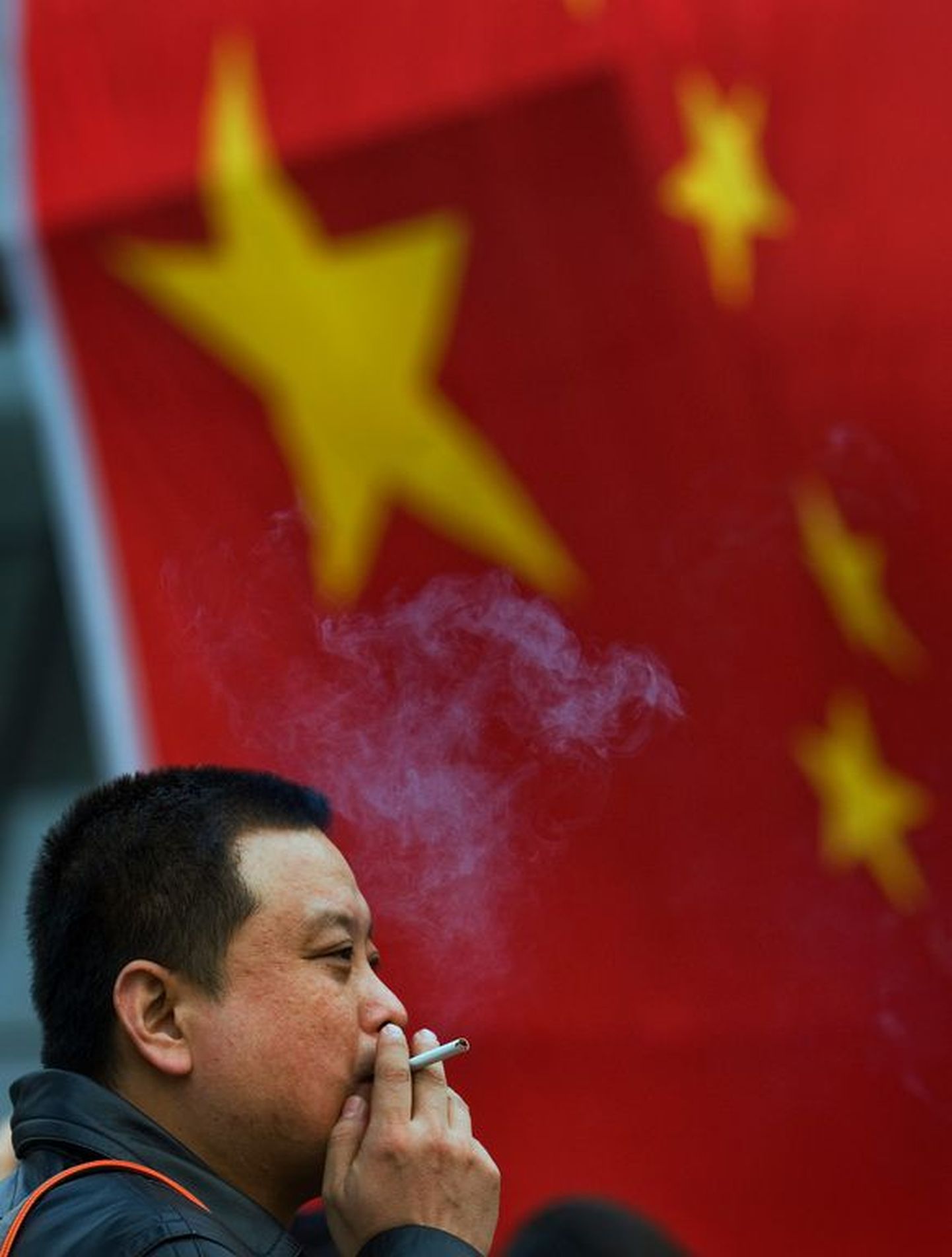 Hiina mees suitsetamas punalipu ees Pekingis.
