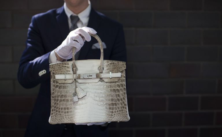 Сотрудник компании Hermes держит сумку модели Birkin из крокодиловой кожи.