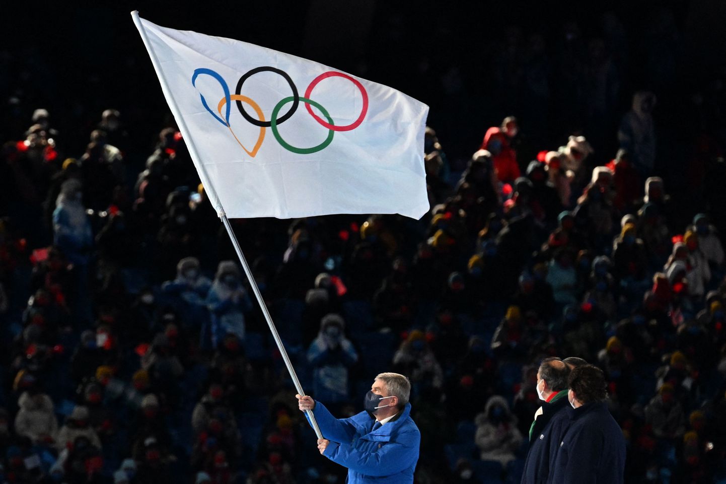 Президент МОК Томас Бах размахивает флагом МОК.