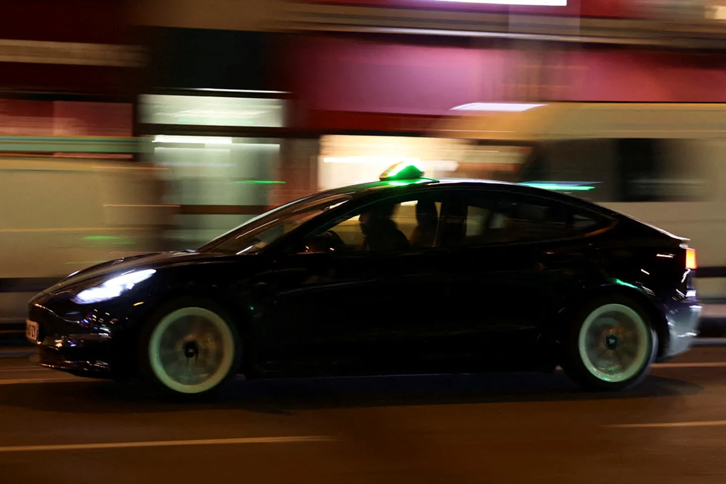 Cilvēks brauc ar "Tesla" automašīnu Parīzē.
