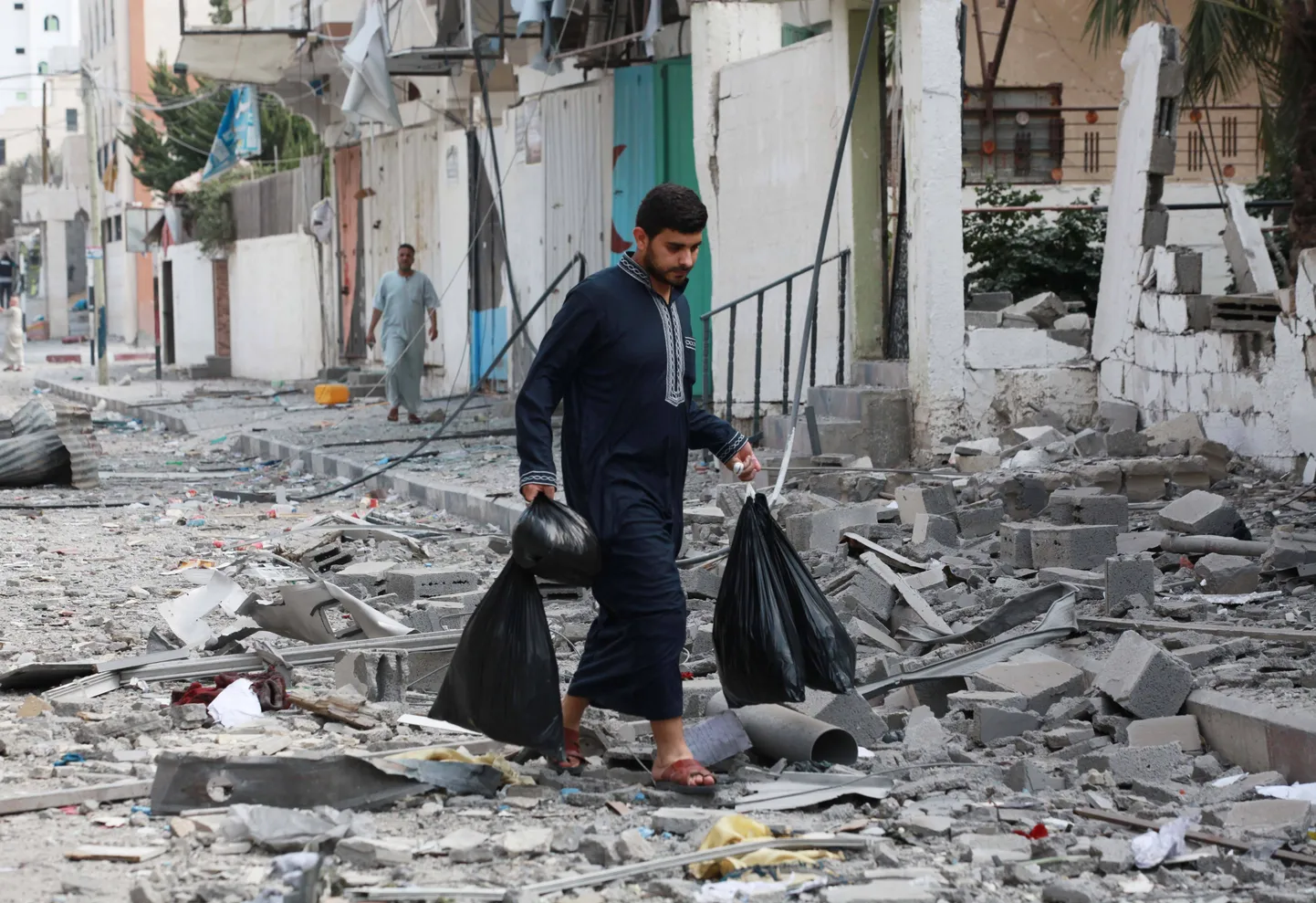Палестинцы идут среди развалин в секторе Газа.