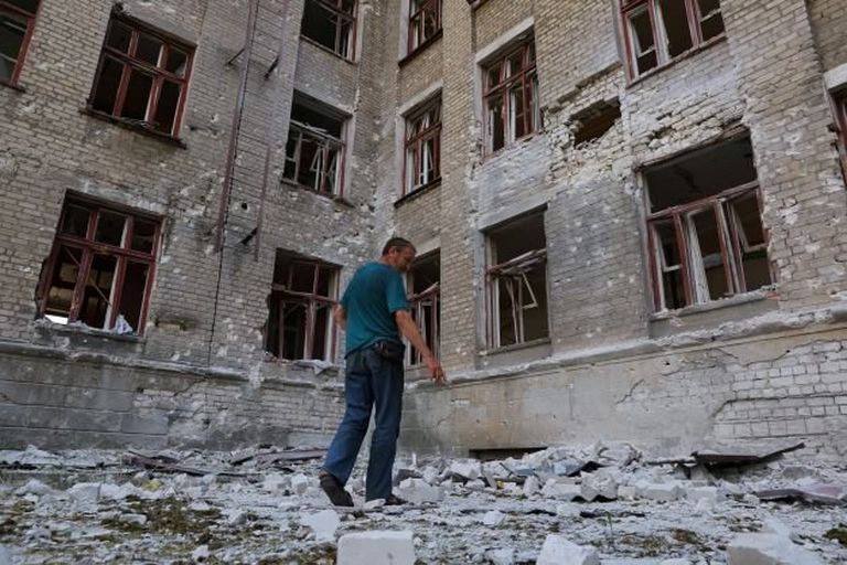 Житель Лисичанская (Луганская область) возле здания разбомбленной школы, в подвале которой он скрывался от обстрелов