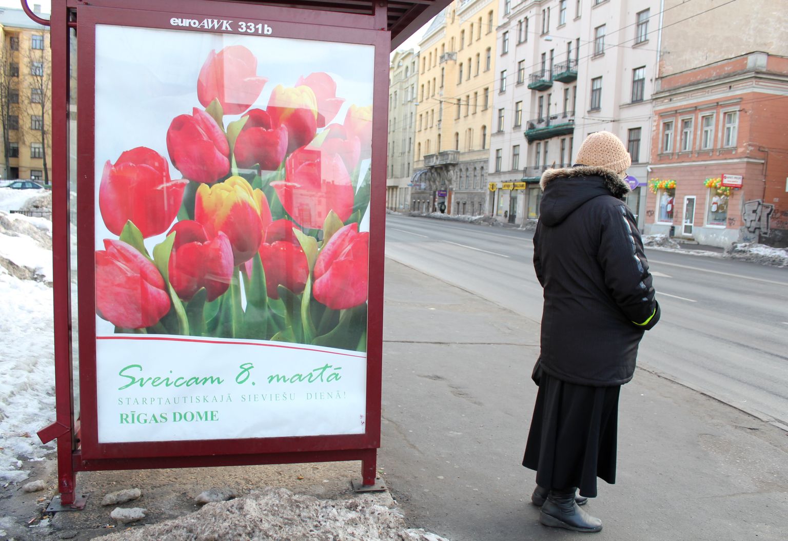 Sieviete pie Rīgas domes apsveikuma plakāta 8. martā, Starptautiskajā sieviešu dienā.