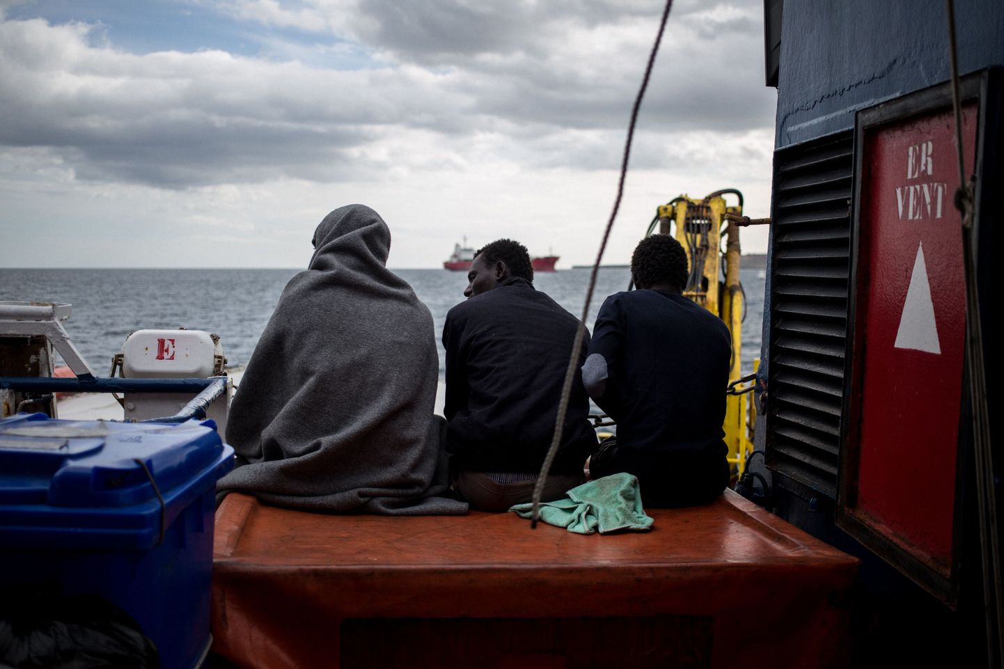 Kolm päästetud paadipõgenikku istumas 30. jaanuaril Hollandi lipu all seilaval abilaeval Sea Watch 3.