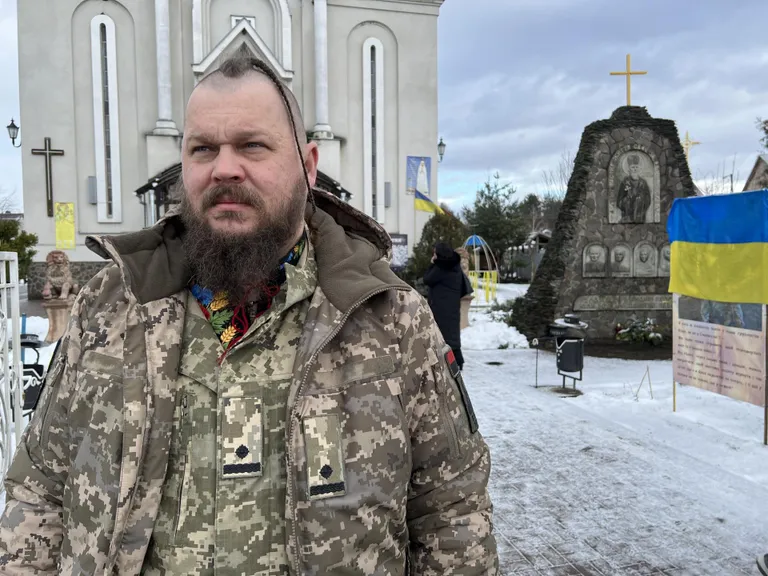Майор Иван Татауров перед католическим храмом на западе Украины. Он вручает семьям крест героя всегда в церкви.