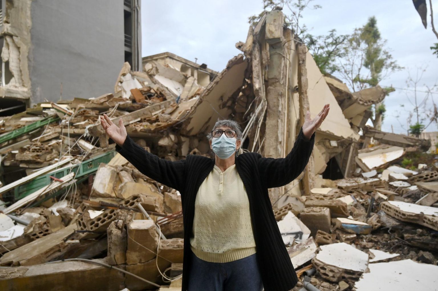 Palveks tõstetud kätega naine tormis ja vihmas kokku varisenud maja ees Ashrafieh’ linnaosas Beirutis. Vana kolmekorruseline maja seisis pärast linna raputanud plahvatusi täiesti tühjana, enne tegutses selle esimesel korrusel jäätisepood. 