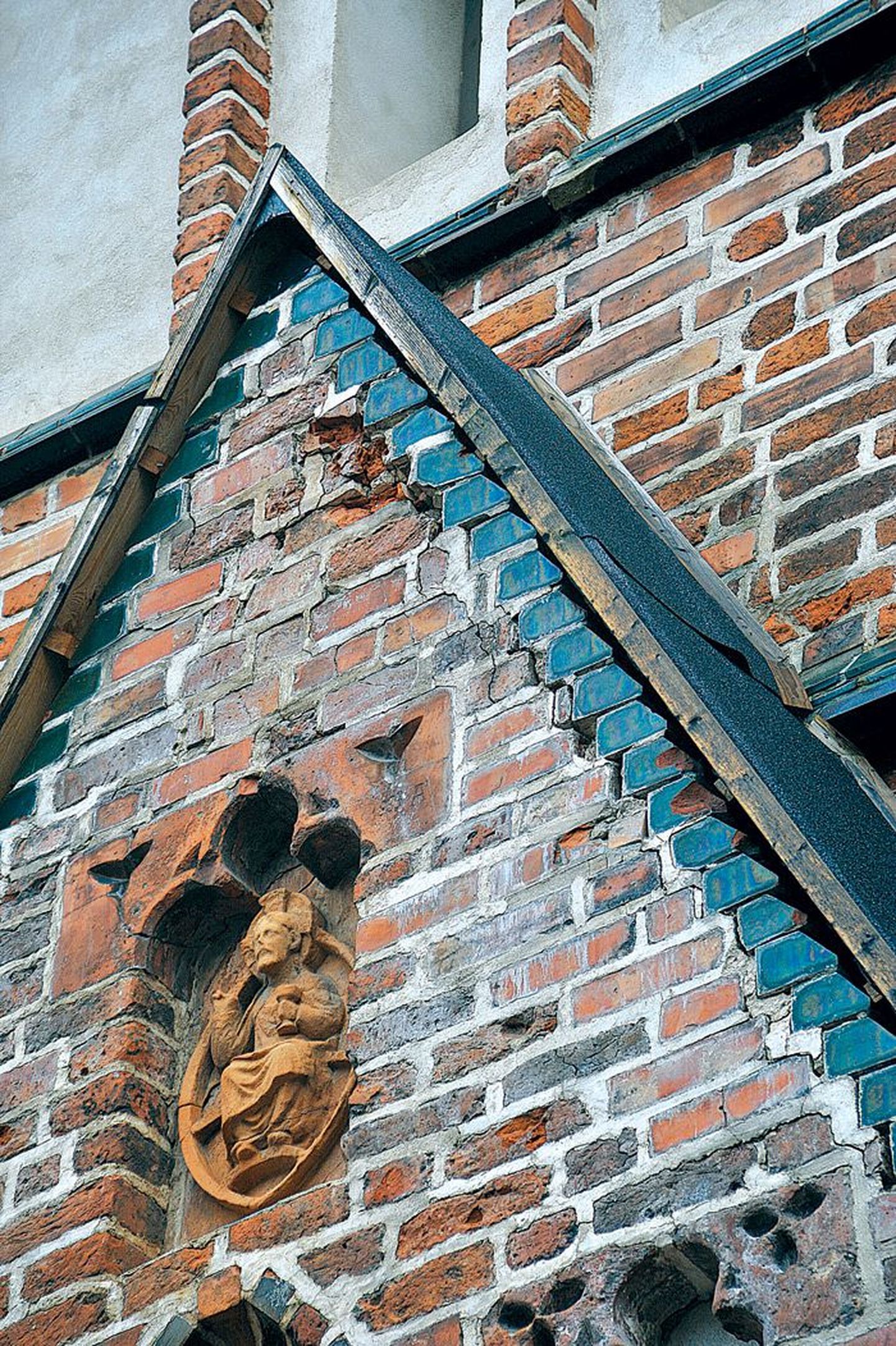 Jaani kiriku peaukse kohal näeb liigniiskuses mõranenud ja kohati pudedaks muutunud tellistega seina. Halvema vältimiseks kaitseb lagunevat portaali ajutine tõrvapapist katus.