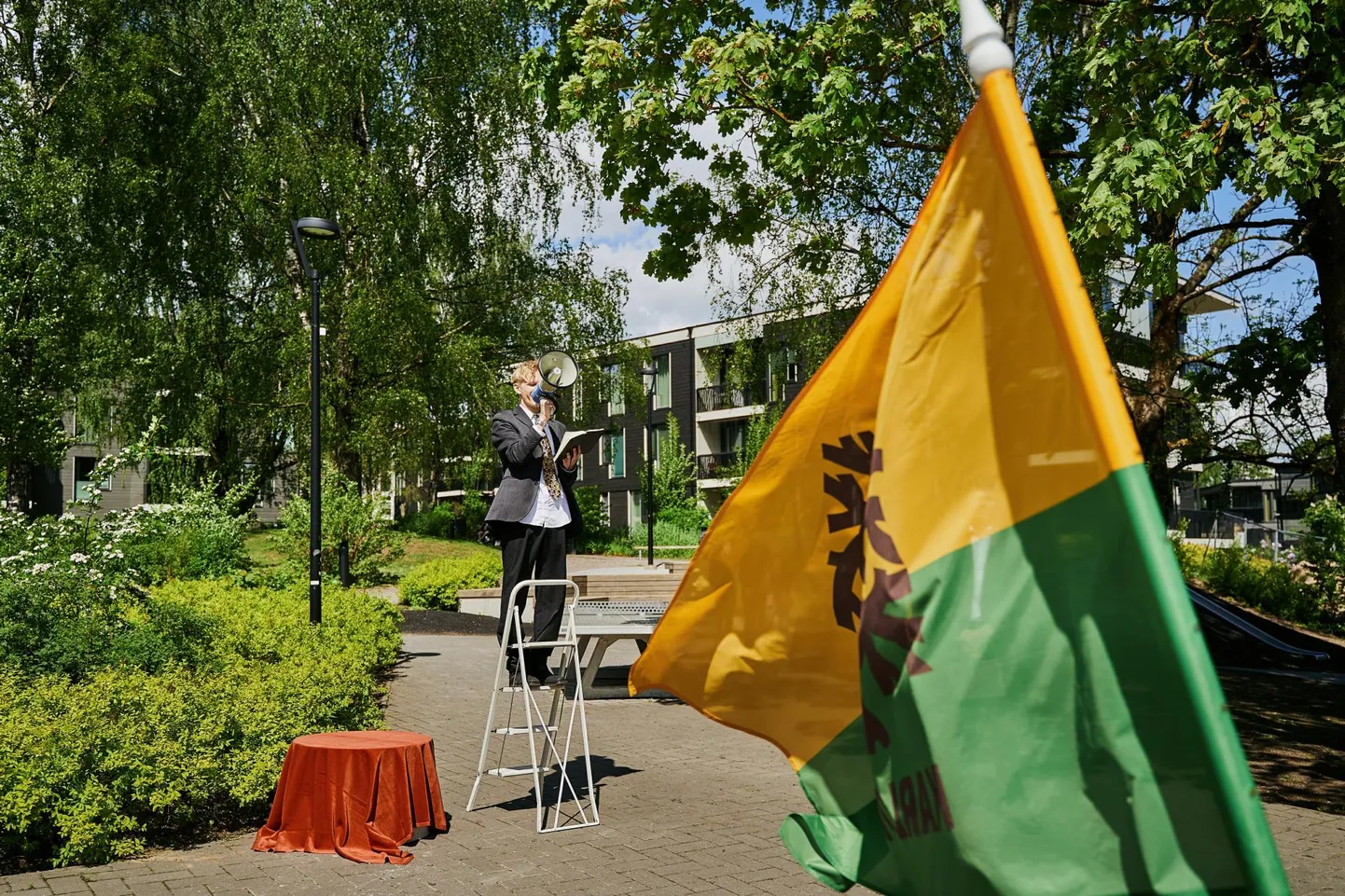Kohtumiste ja Mitte-Kohtumiste Instituudi dramaturg Oliver Issak juhatas Pargi ja Tähe nurgal mänguväljakul veel katte all oleva monumendi avamise tseremooniat. Lehvib Karlova lipp.