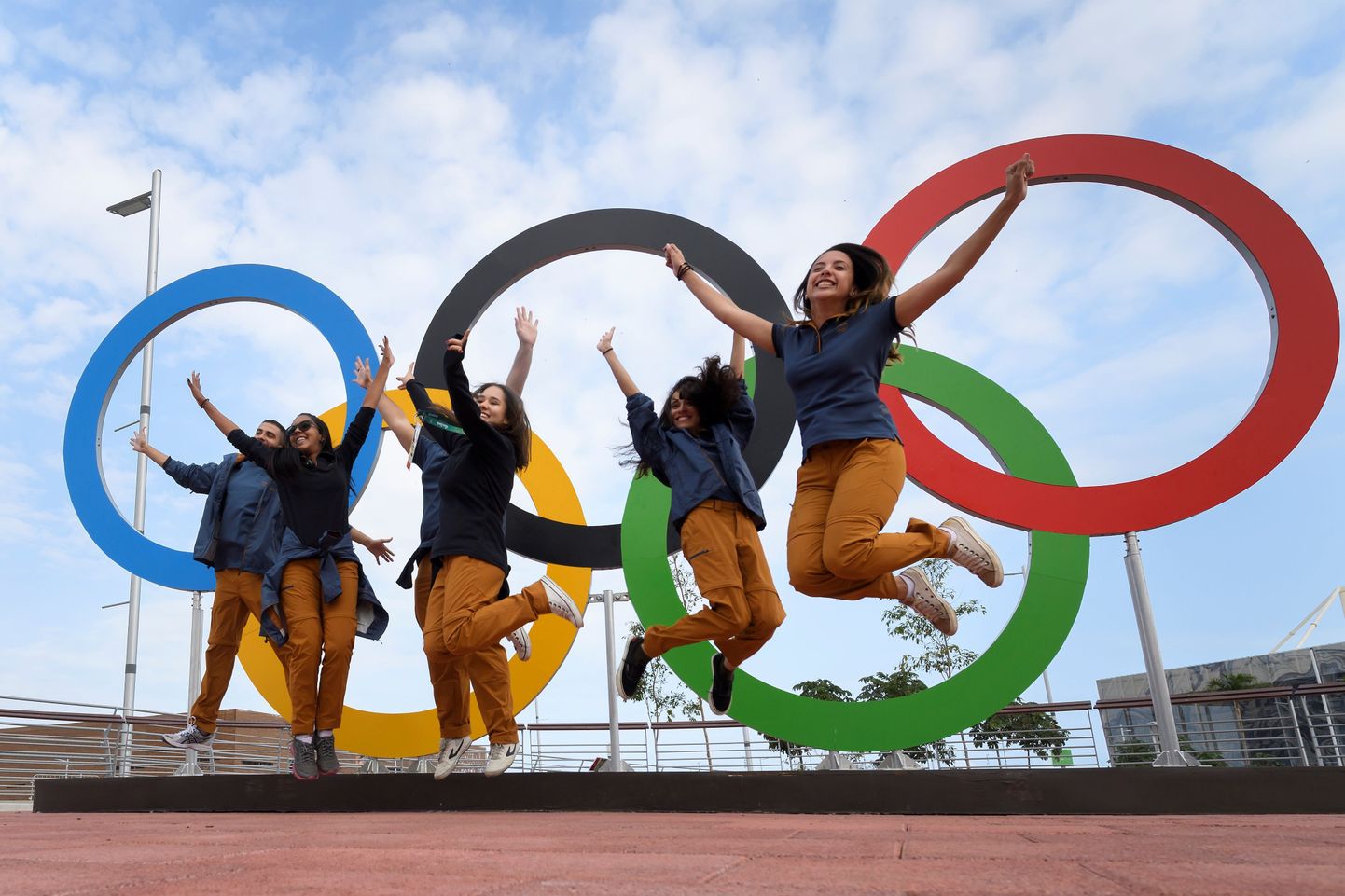 People jump for a picture in front of Olympic Rings set at the Olympic park in Rio de Janeiro on August 3, 2016.