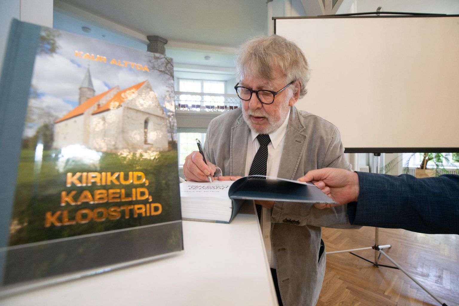 Kaur Alttoa andis Tartu ülikooli muuseumi valges saalis oma vastse artiklikogumiku tiitellehele autogrammi.