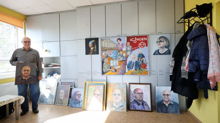 Andres Meritsa portreed kõik põrandal maas. Käes hoiab ta Tiiu Hanseni maalitut.