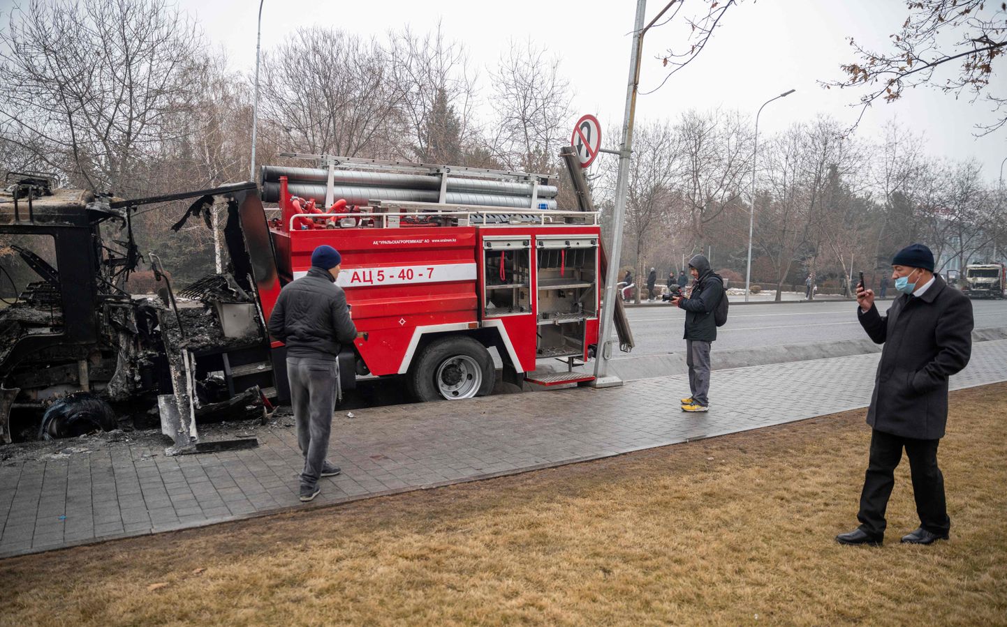 Märgid rahvarahutuste tagajärgedest Almatõs. Möödujad pildistavad põlema pandud  päästemasinat kesklinnas.
