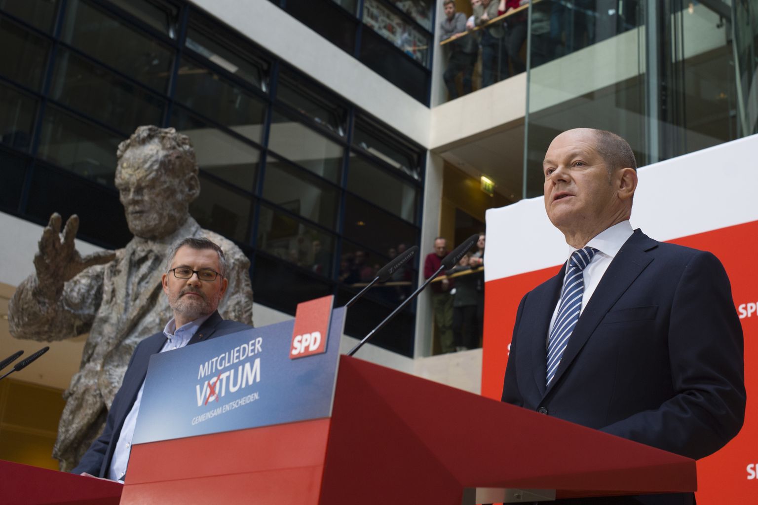 SPD finantsjuht Dietmar Nietan (vasakul) ja ajutine esimees Olaf Scholz teatasid tulemustest endise kantsleri Willy Brandti kuju valvsa pilgu all.