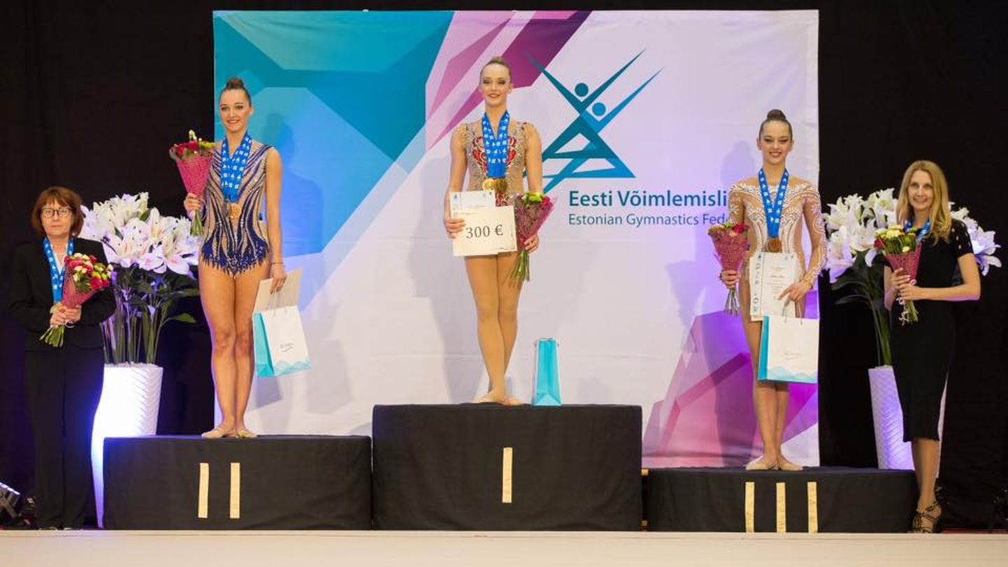 Iluvõimlemise meistriklassi absoluutse arvestuse medalikolmik (vasakult) – Viktoria Bogdanova, Carmen Marii Aesma, Melany Keler treeneritega.