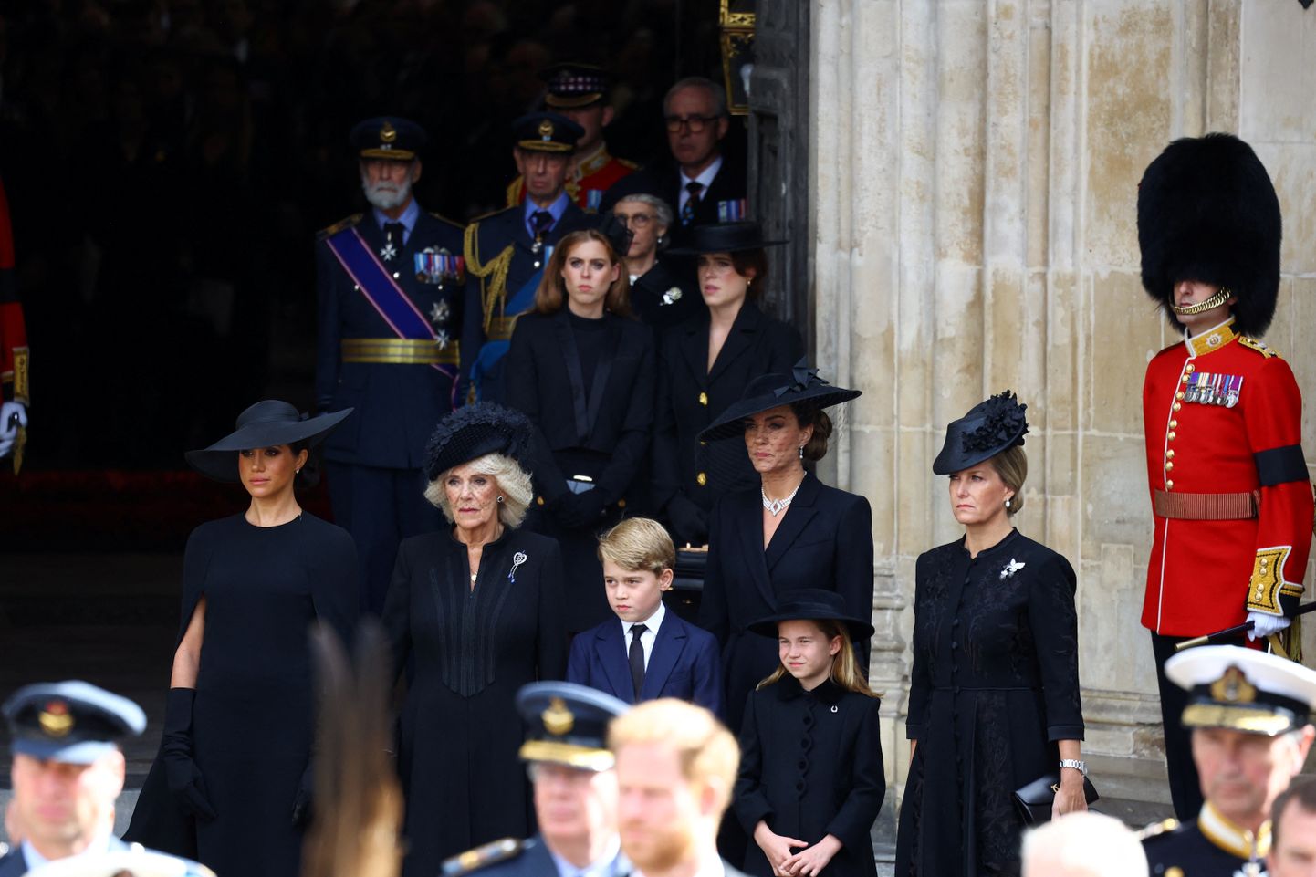 Kuninganna Elizabeth II matuse rongkäiku jälgivad prints Harry abikaasa Meghan, kuninganna Camilla, prints George, Walesi printsess Catherine, printsess Charlotte ja Wessexi krahvinna Sophie. Taamal seisavad printsess Beatrice ja printsess Eugenie.