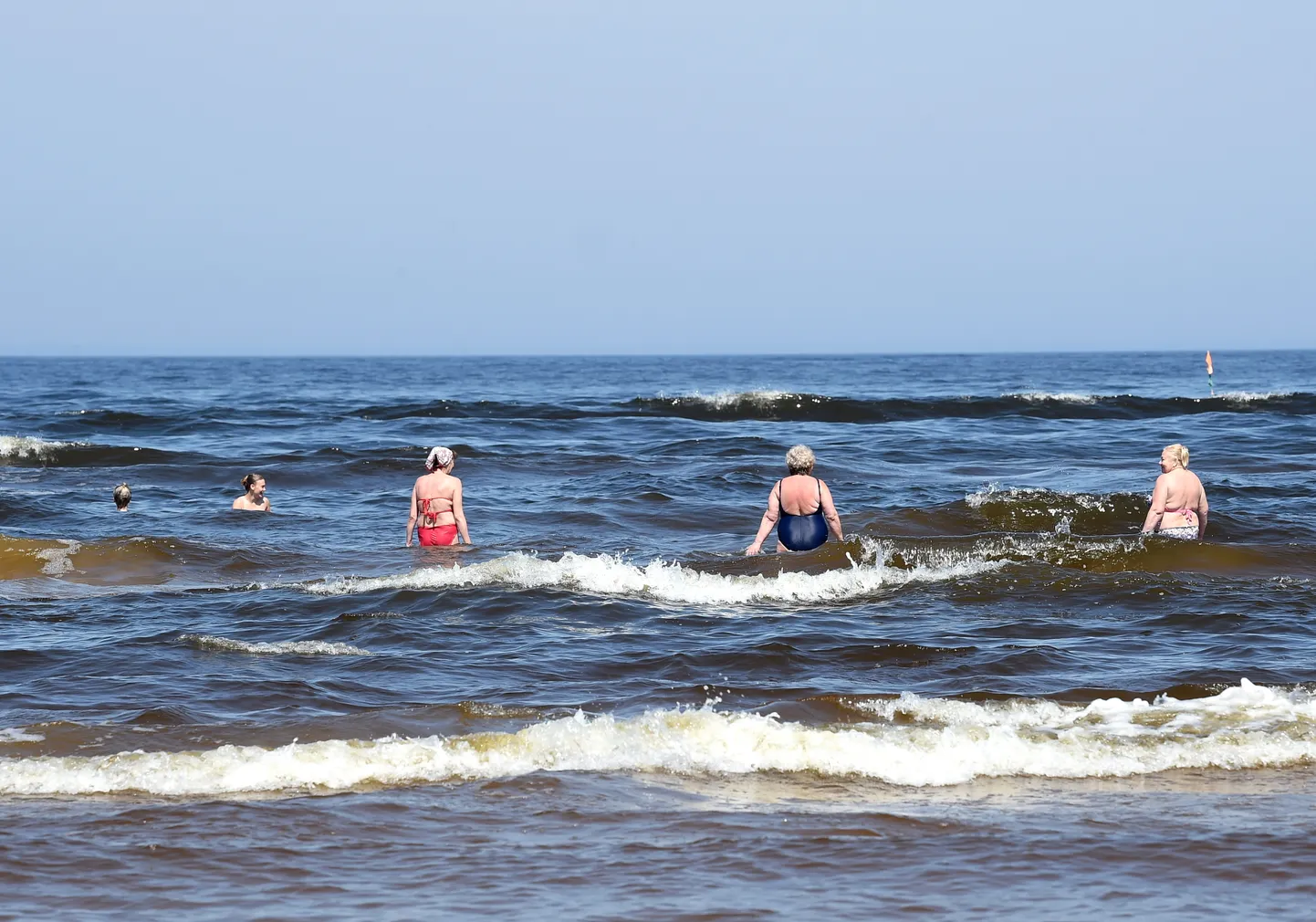 Cilvēki peldas Vecāķu pludmalē.