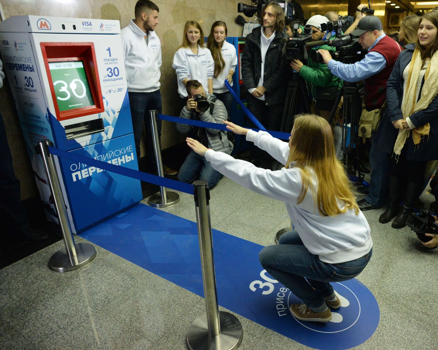 Noor naine kükitab piletimasina ees, mis müüb metroopileteid raha asemel kükkide eest.