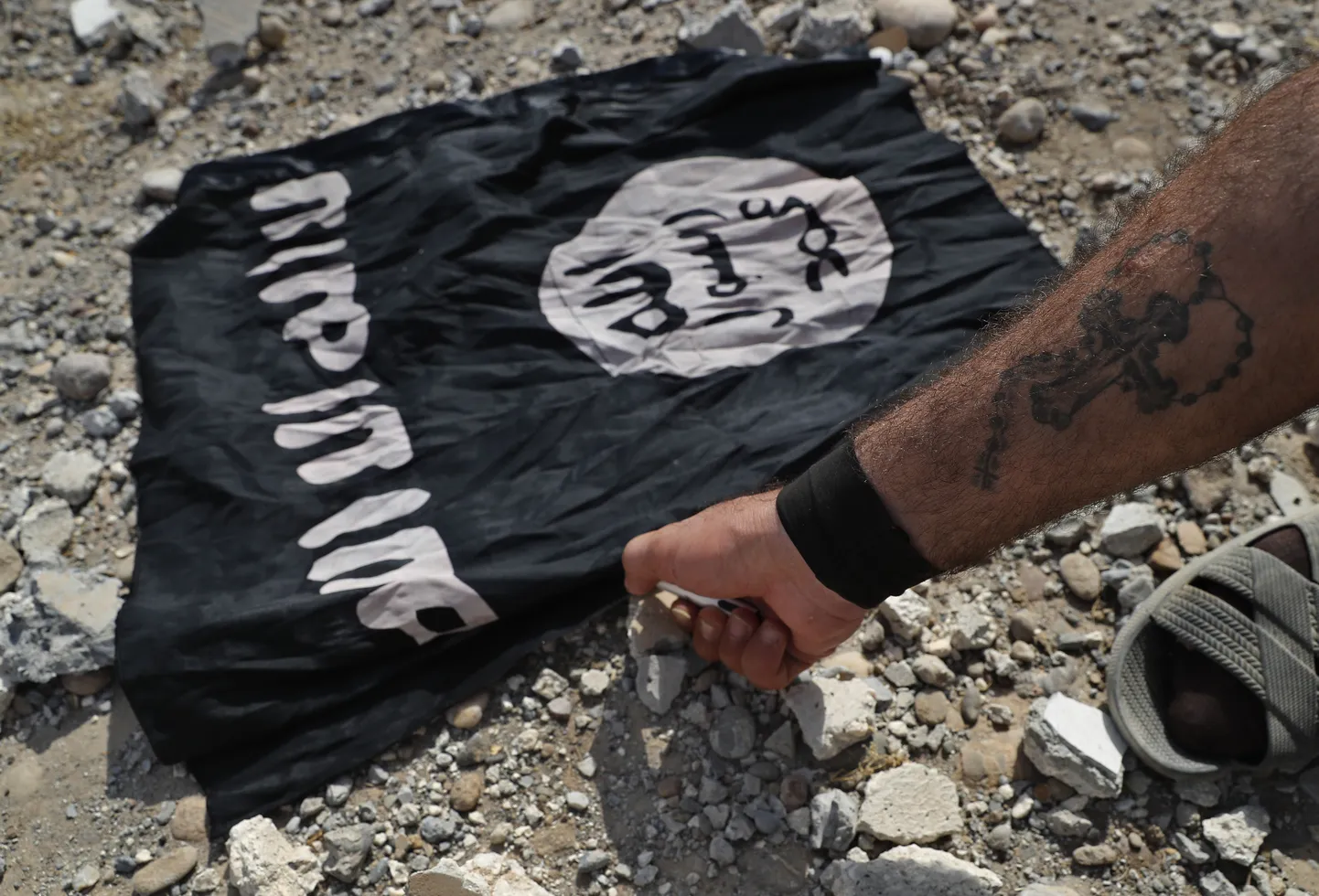 A fighter of Christian Syriac militia that battles the Islamic State group under the banner of the U.S.-backed Syrian Democratic Forces, burns an IS flag on the front line on the western side of Raqqa, northeast Syria, Monday, July 17, 2017. U.S.-backed Syrian fighters fought Islamic State militants in the heart of Raqqa, the extremists' self-styled capital, as scores of civilians fled areas controlled by the group. (AP Photo/Hussein Malla)