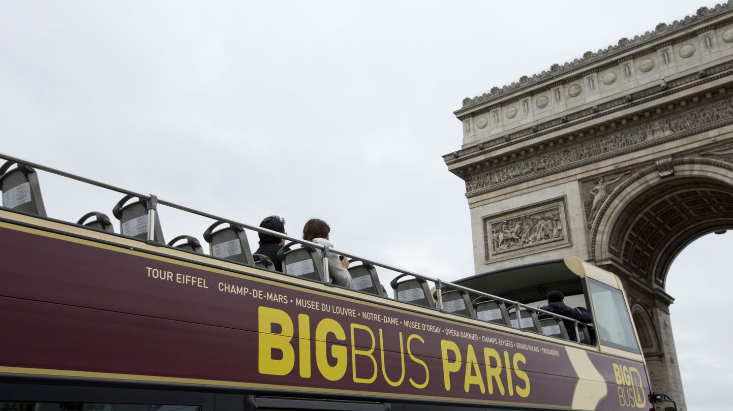 Üksikud turistid Pariisi Triumfikaare alt läbi sõitvas ekskursioonibussis.