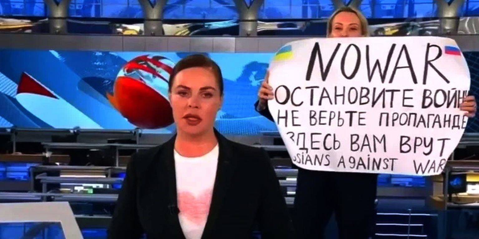 Ведущая новостей Екатерина Андреева. На фоне - Марина Овсянникова с антивоенным плакатом