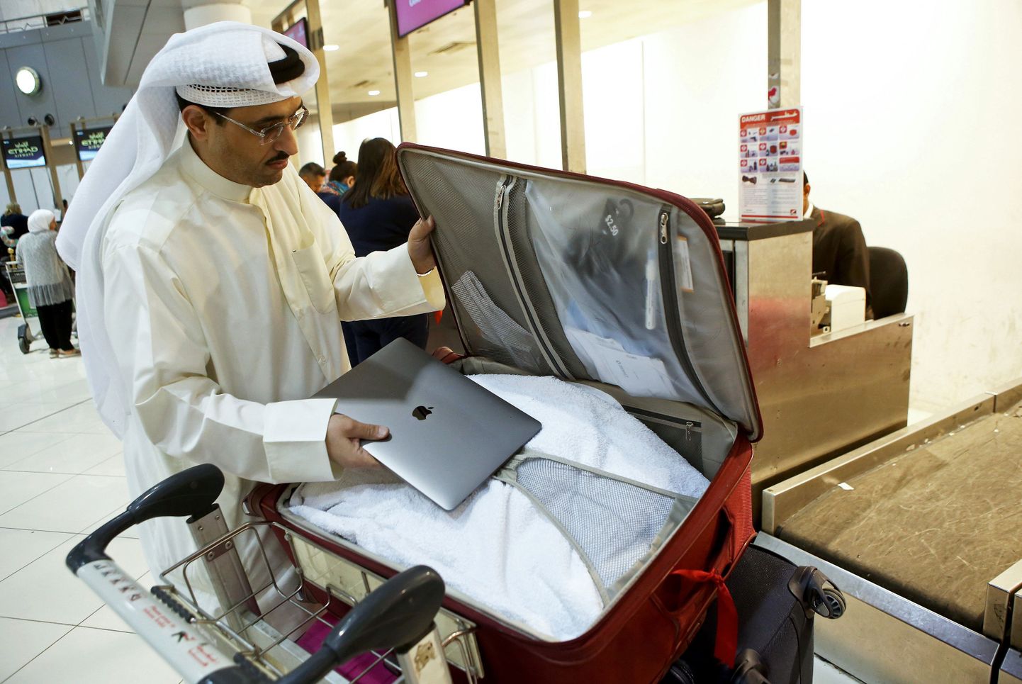 Kuveidi reisija pakib sülearvuti äraantava pagasi hulka.
