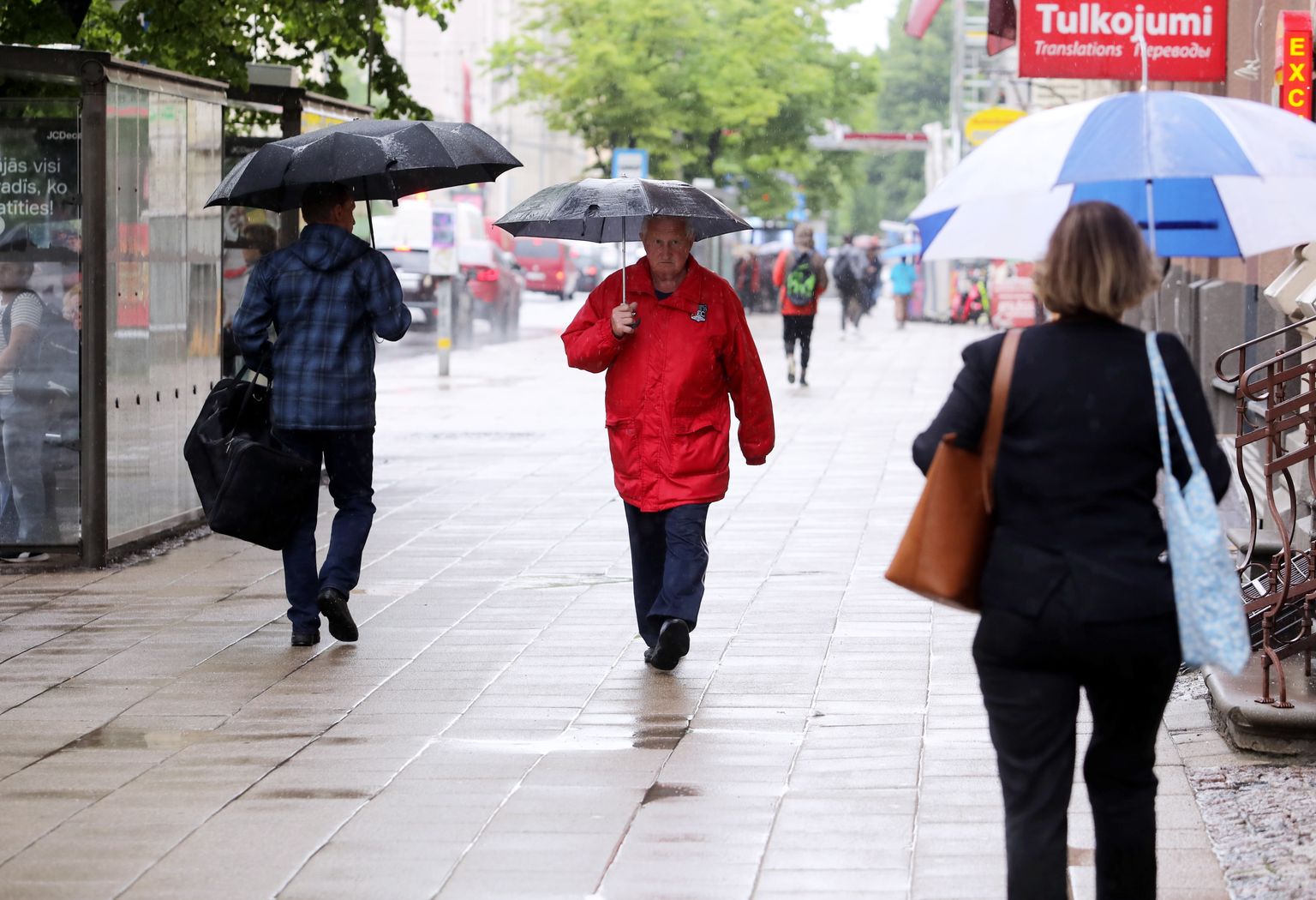 Cilvēki ar lietussargiem Merķeļa ielā