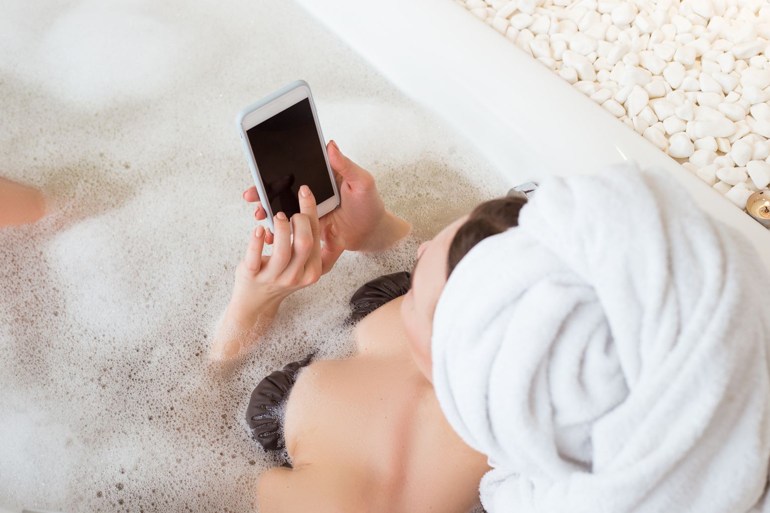 Pilt on illustreeriv: naine telefoniga vannis.