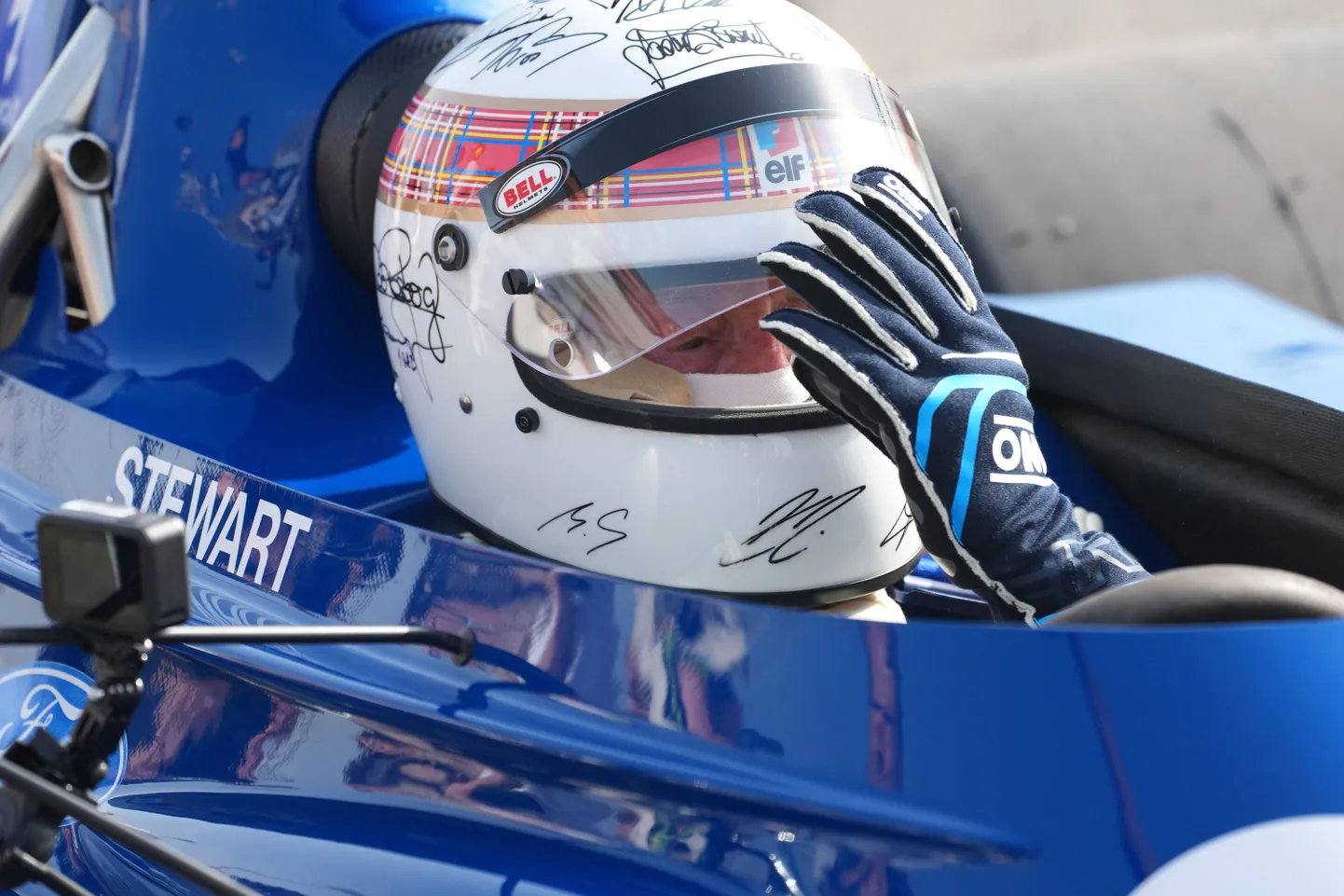 Jackie Stewart надевает шлем, который будет выставлен на аукцион, с автографами всех живых чемпионов мира Формулы-1.