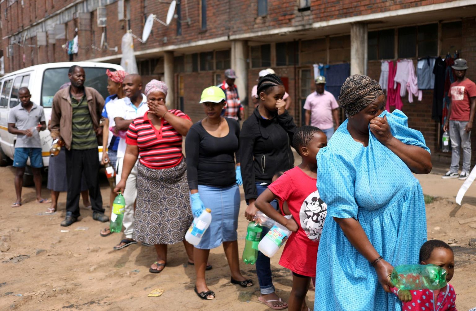 Nägu rõivastega kaetud ja tühjad plastpudelid käes, ootavad Lõuna-Aafrika Vabariigi linna Alexandra elanikud järjekorras, et tervishoiutöötajad neile desinfektsioonivahendeid annaksid. 