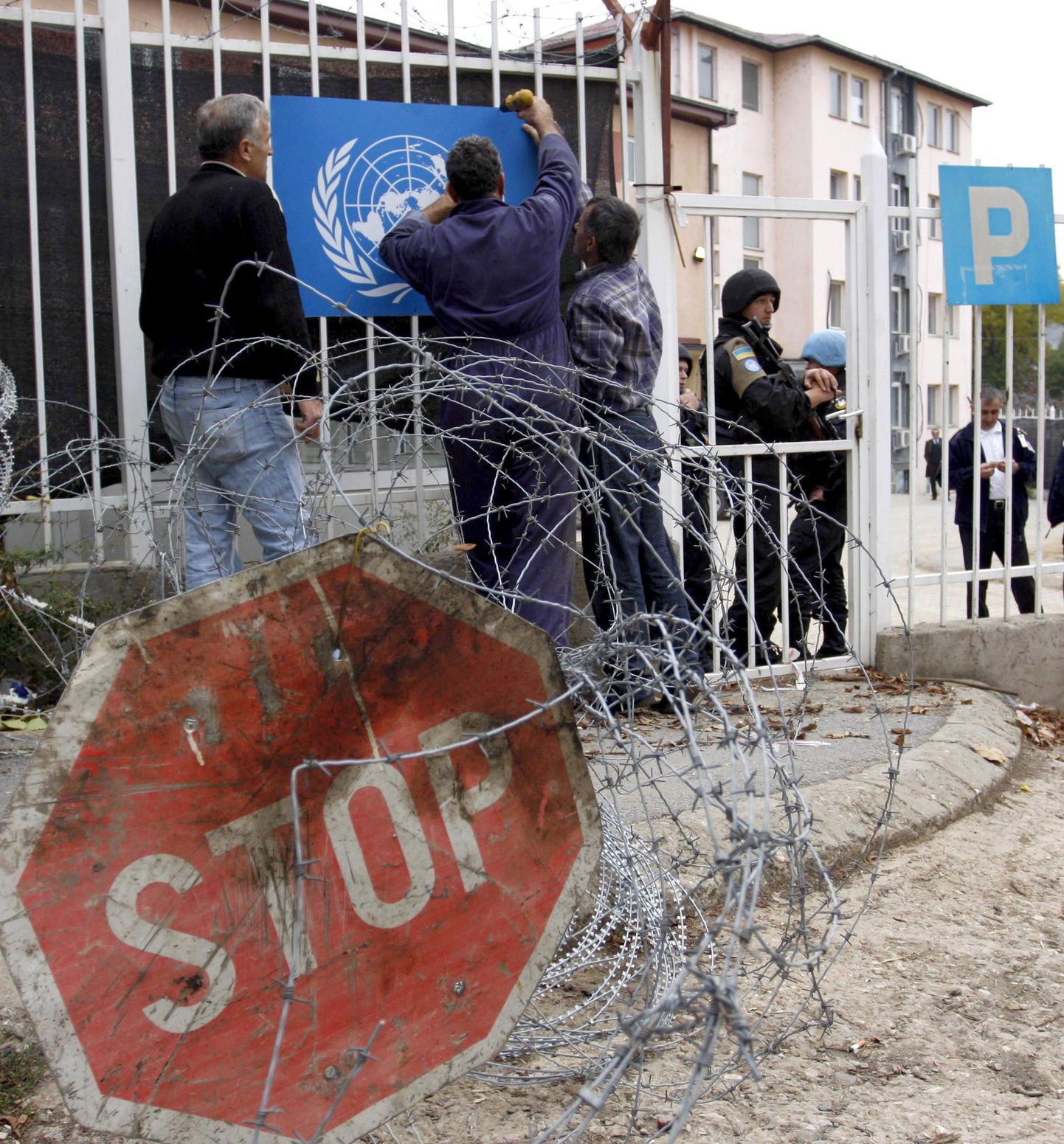 Töötajad paigutamas ÜRO embleemi Mitrovicas asuva ÜRO kohtuhoone väravale.
