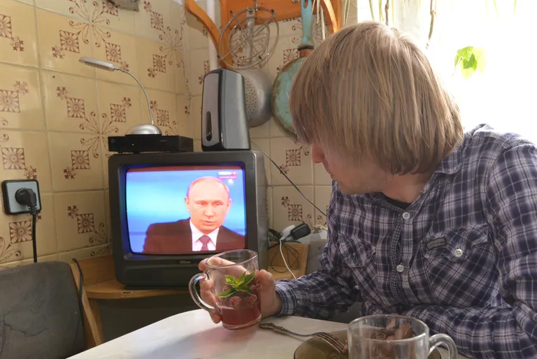 Vene mees vaatab televiisorist president Vladimir Putini kõnet. / Scanpix