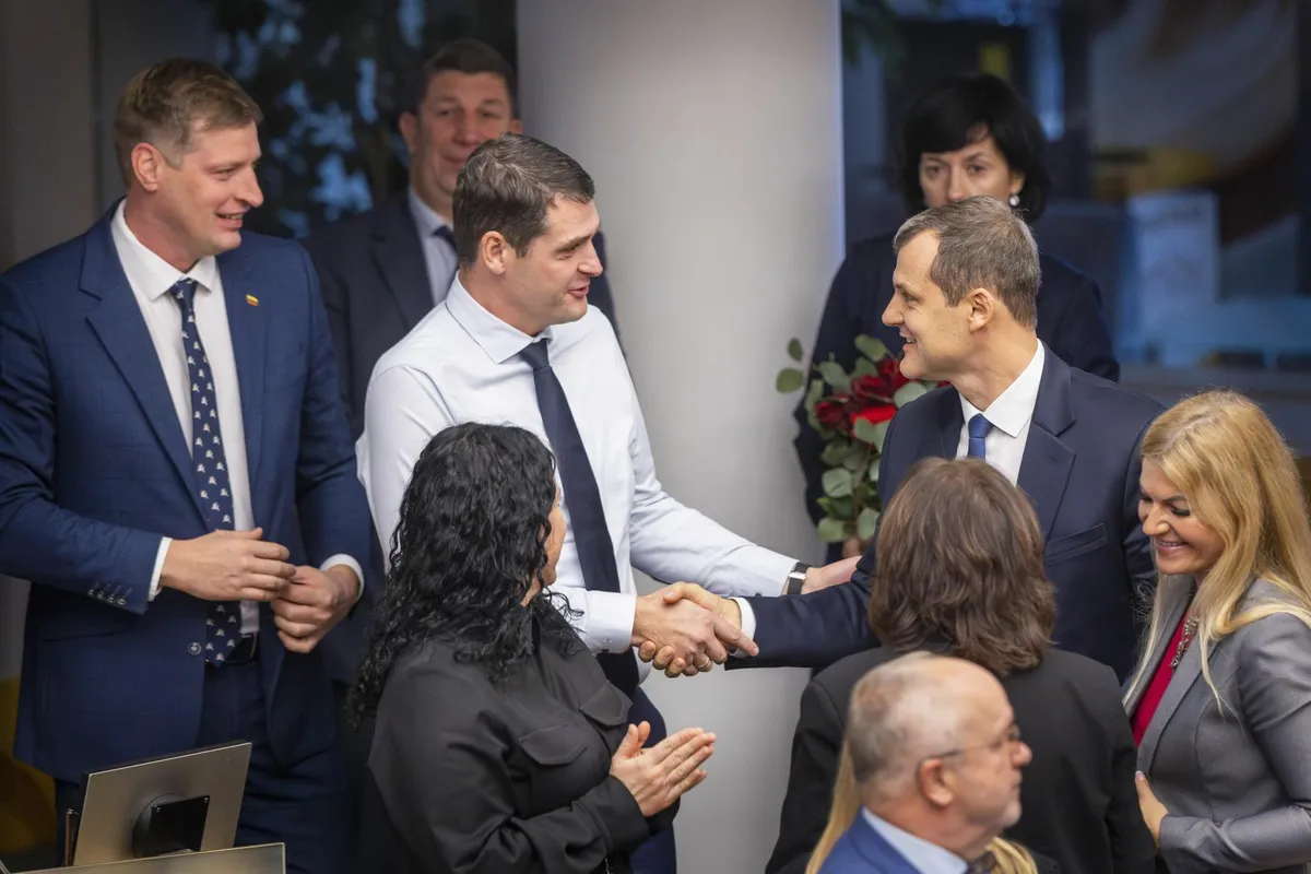 Nemunase Koidu esimees Remigijus Zemaitaitis (vasakul teine) kätleb Leedu sotsiaaldemokraatide peaministri Gintautas Paluckasega (paremal) pärast ühise koalitsioonileppe sõlmimist, 21. novembril 2024. a. Valitsusse kuulub ka partei Demokraadid Leedu Eest.