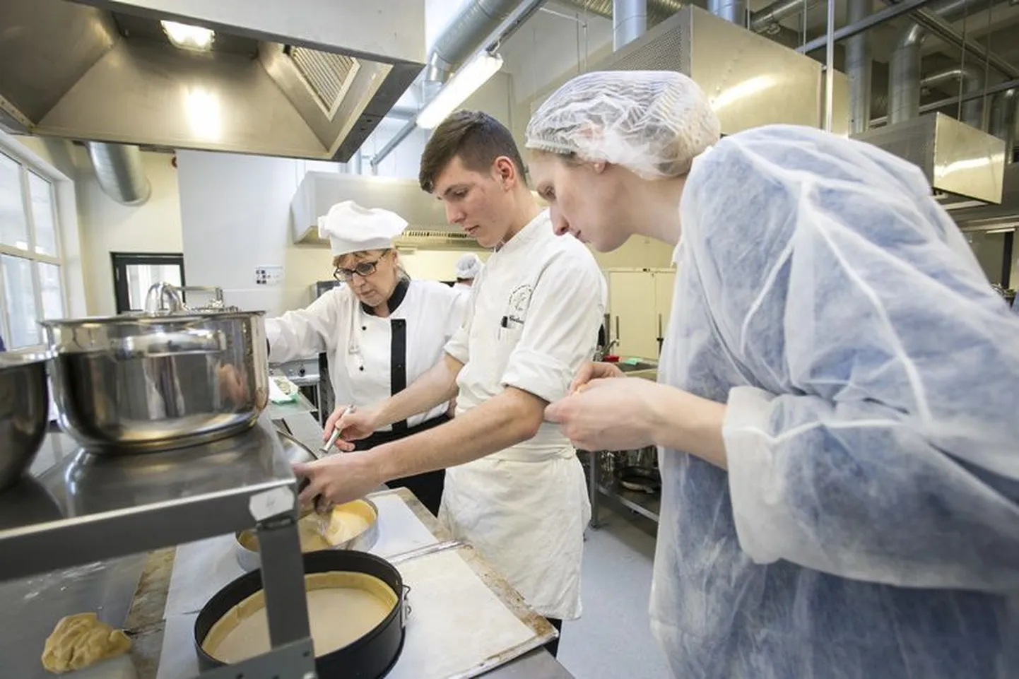 Esimese täidise valamine: noor prantsuse maiuseekspert (keskel) näitab Rakvere ametikooli õpetajatele ­ette prantsuspärase sidrunikoogi küpsetamist.
