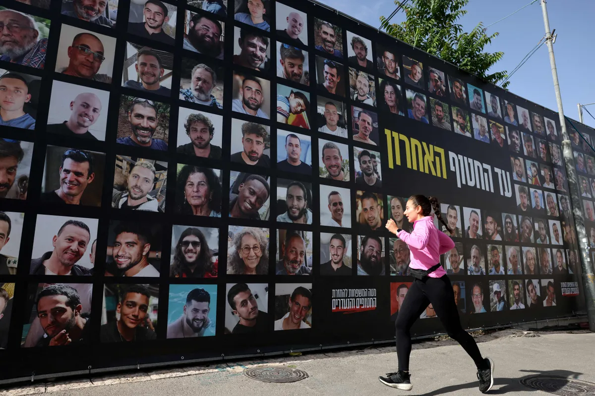 A woman jogs past a billboard bearing the portraits of Israeli hostages, held in the Gaza Strip since the October 7, 2023 attacks by Hamas militants, in Jerusalem on May 13, 2025.