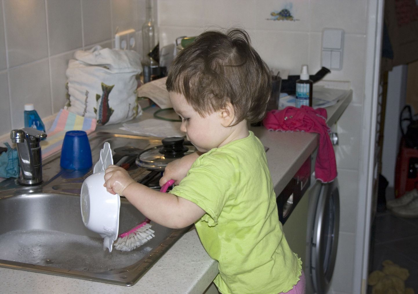 Ребенок моет посуду.
