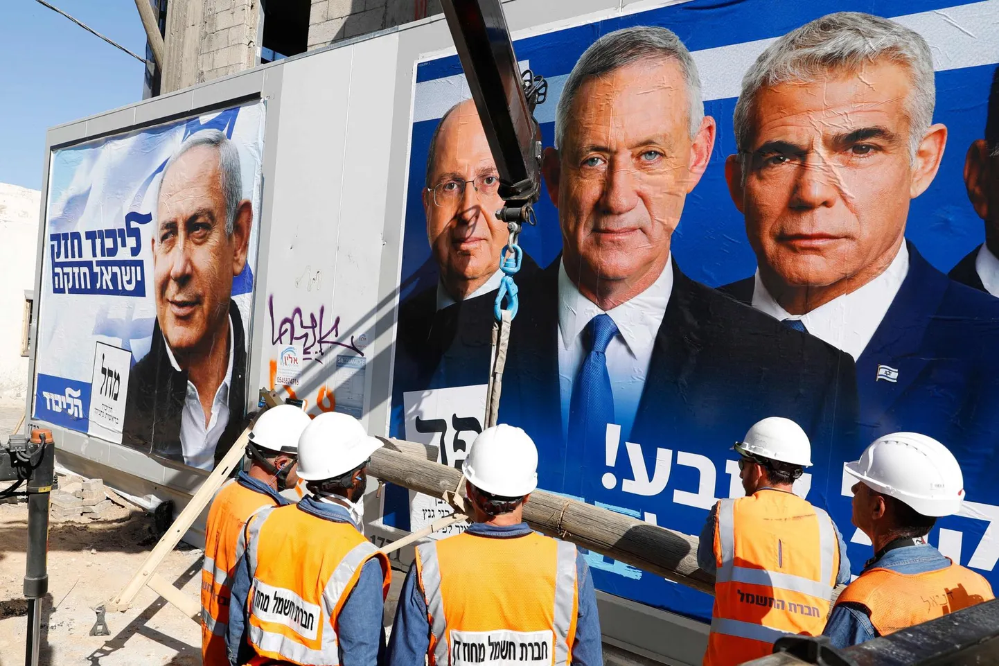 Töömehed toimetavad Tel Avivi tänaval valimisplakatite ees. Vasakul silmitseb neid Likudi liider Benjamin Netanyahu, parempoolsel plakatil erukindral Benny Gantz (esiplaanil), kes on üks valimisliidu Kahol Lavan juhtidest. 
