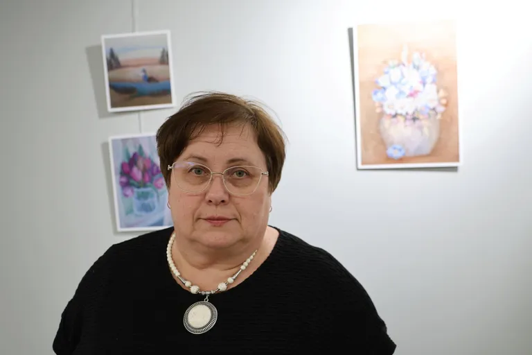 Tiia Zeigo selja taga ta enda maalitud maastik õngitsejaga ja lillepildid.