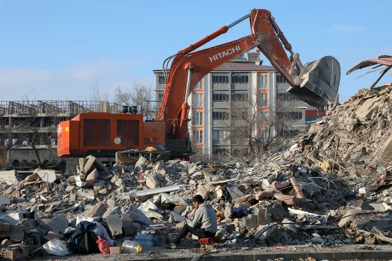 Mees istumas 19. veebruaril 2023 Türgis Kahramanmarases maavärinate järel oma maja rusudel. Taamal on buldooser, millega majajäänused kokku korjatakse