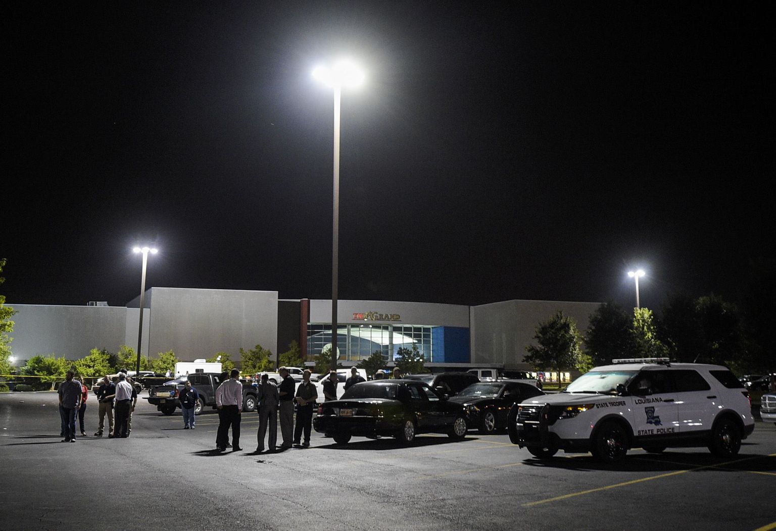 Law enforcement personnel stand in the parking lot of The Grand Theatre early Friday, July 24, 2015, in Lafayette, La., as they investigate a shooting from the night before. (Paul Kieu'The Daily Advertiser via AP)  NO SALES; MANDATORY CREDIT