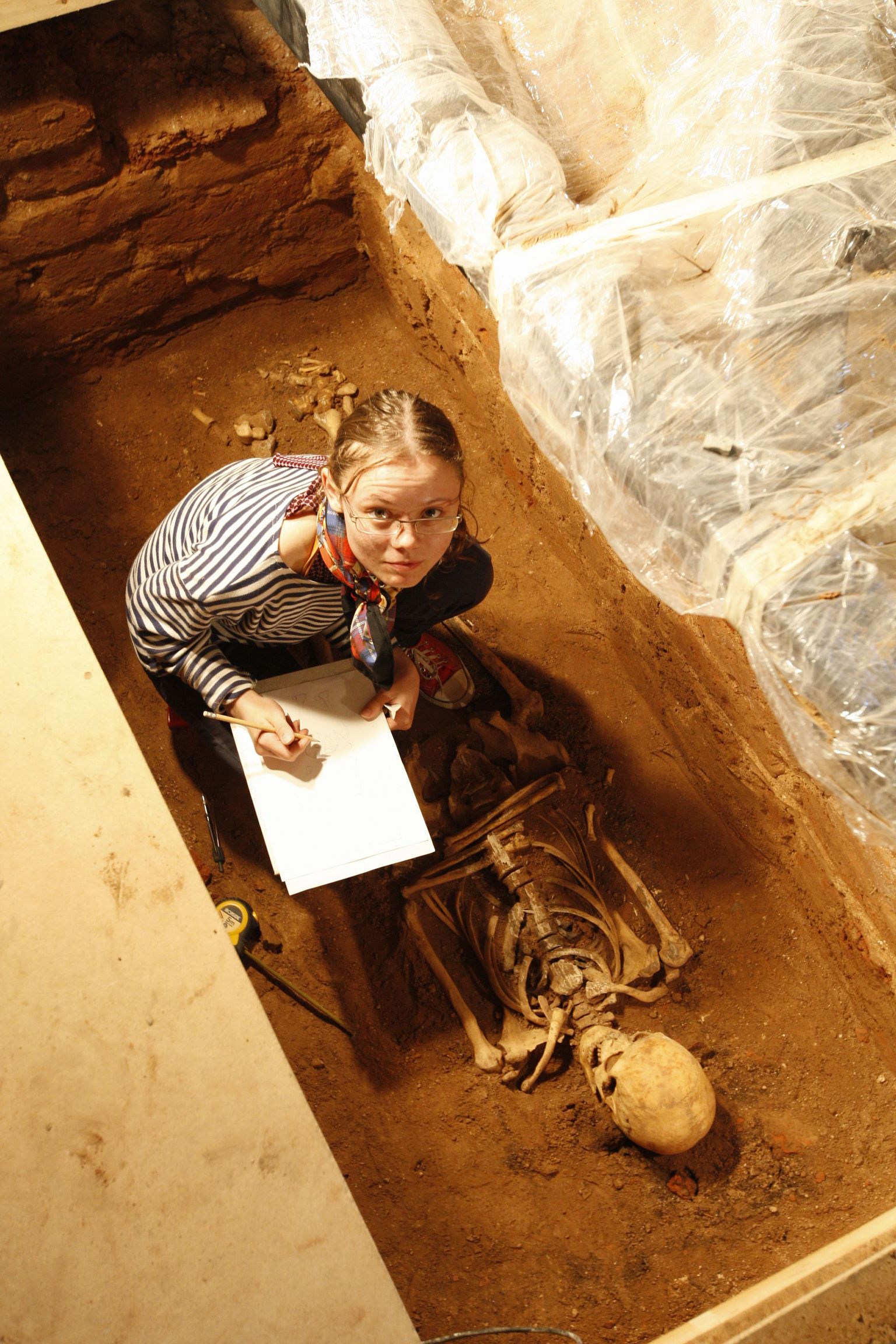 Märtsis TÜ ajaloo muuseumi fuajeest kaevamiste käigus avastatud hauakastist leiti eile matus. Pildil mõõdab Evelyn Fridolin leitud skeletti.