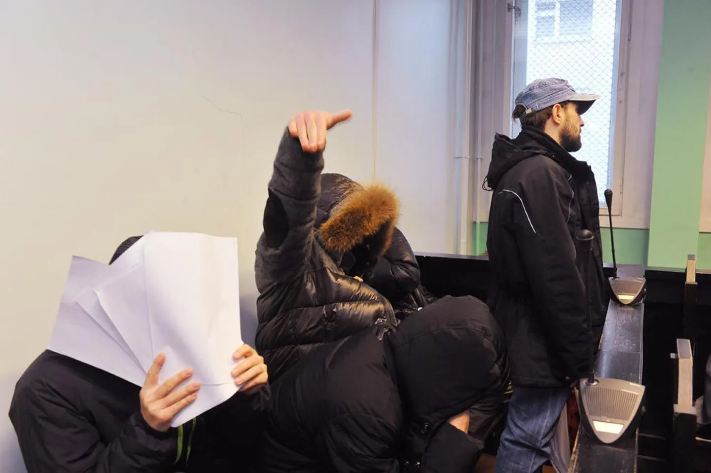 Süüpingis istuvad kohtualused protesteerisid pildistamise vastu nägusid varjates. Konstantin Dmitrijev pidi kohtule selgituste jagamise ajaks siiski käed näo eest ära võtma.
