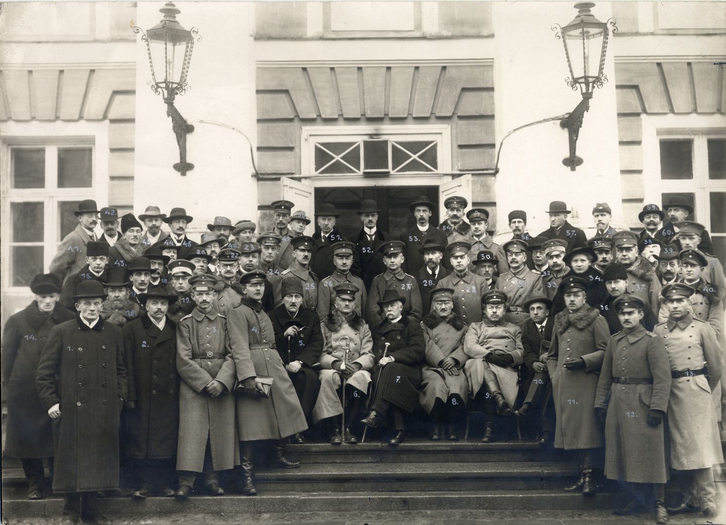 Landesuniversitäti õppejõud ja teenistujad 1918. aasta oktoobris ülikooli peahoone trepil. Võimalik, et Hans Helfritz saatis selle foto oma peamisele nõuandjale Preisi haridus­ministeeriumis Carl Beckerile. Ilmselt seetõttu on kõik inimesed pildil ka nummerdatud.