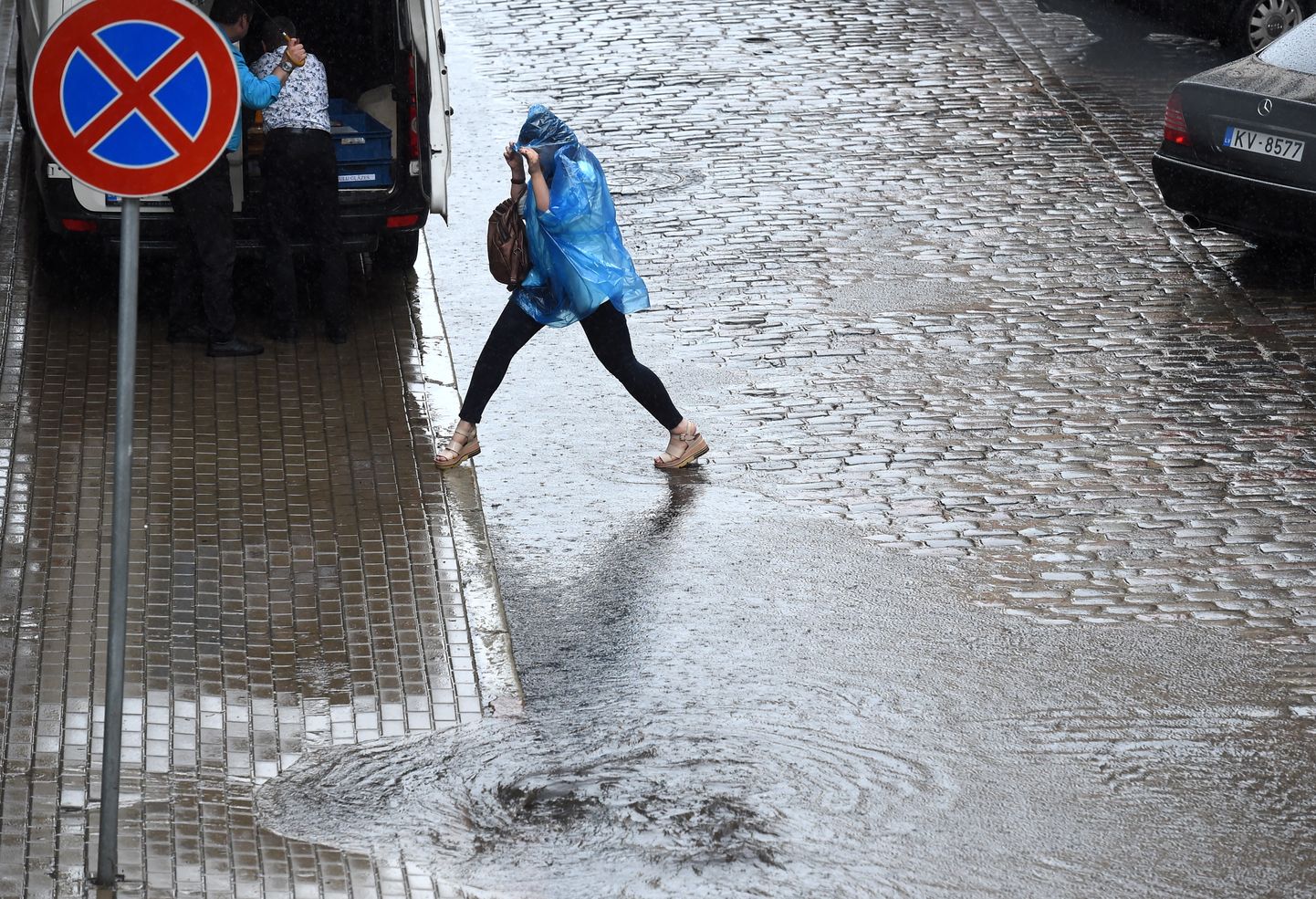 Cilvēki pielijušajā Marijas ielā pēc spēcīgās lietusgāzes.