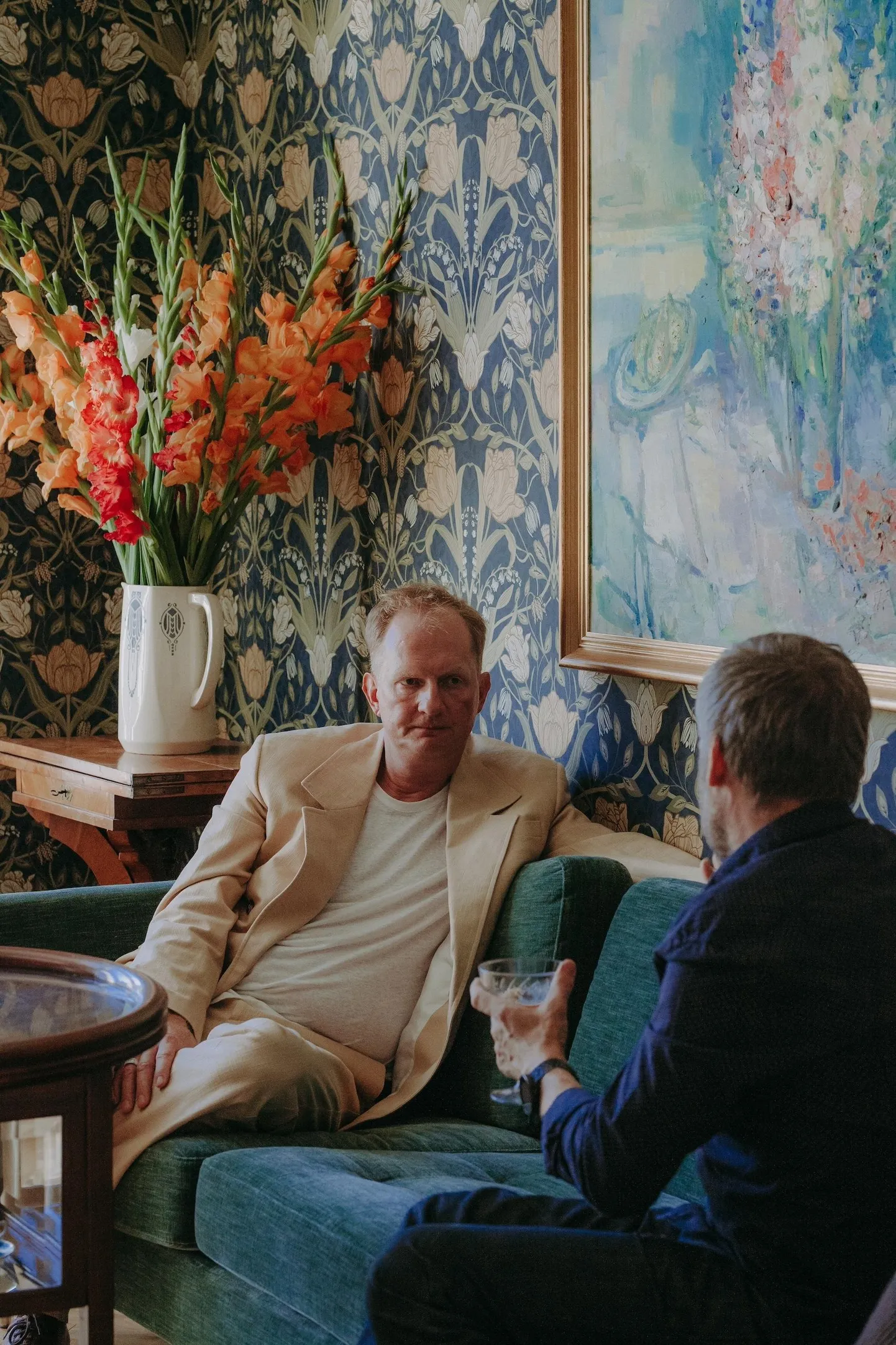 Kristian Taska vestlemas Pärnu majas filmi «Vari» režisööri Jaak Kilmiga. Paremal paistab Aleksander Vardi maal, lilled laual püüavad Taska sõnul seda peegeldada.