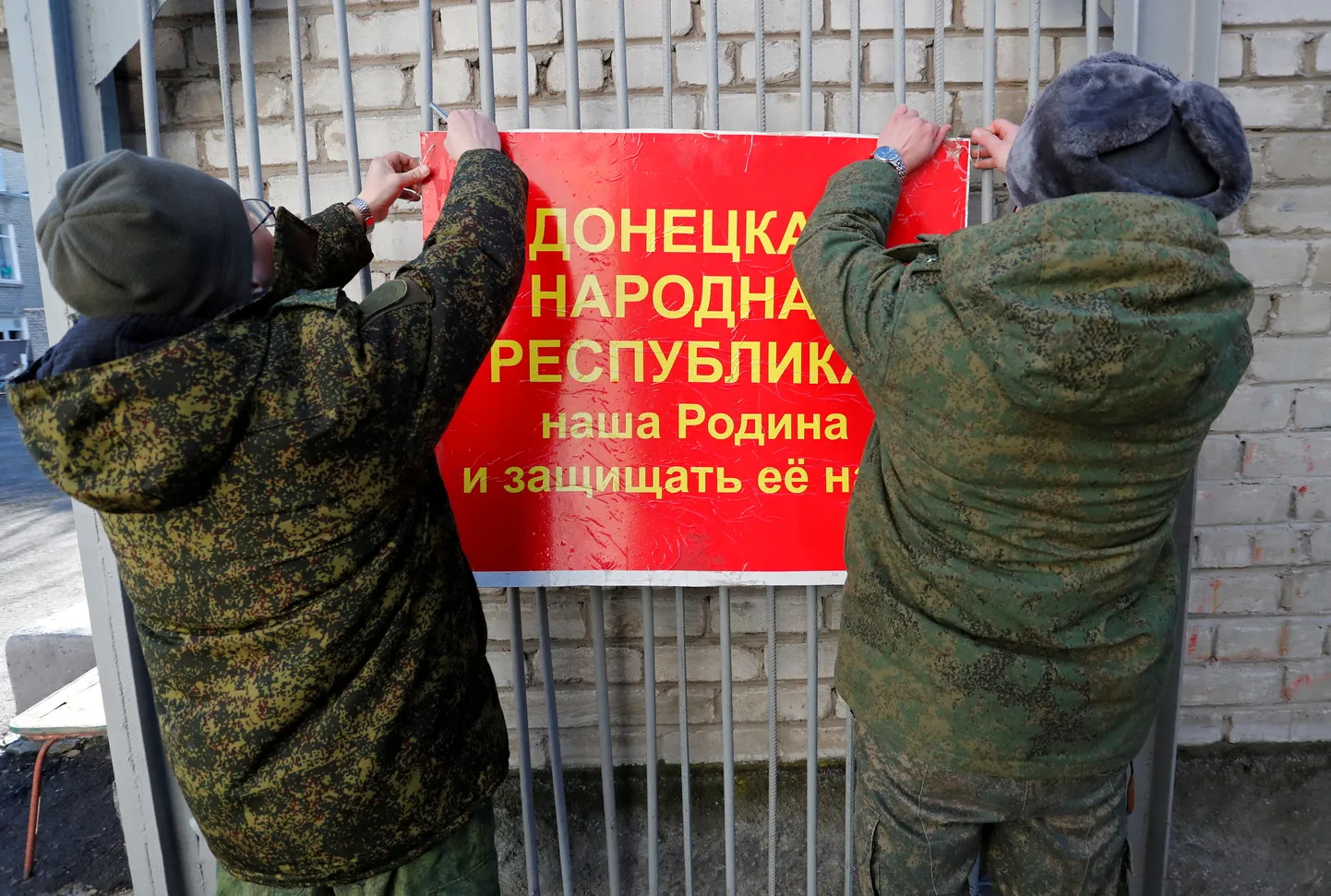 Февраль 2022 года. Ополченцы так называемой ДНР вешают патриотический баннер.